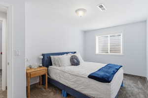 Bedroom with dark colored carpet and a textured ceiling