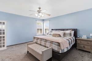 Carpeted bedroom with ceiling fan and baseboards