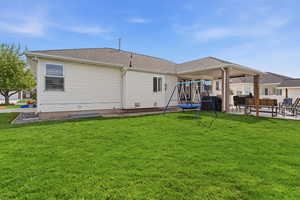 Back of property featuring a patio, roof with shingles, a trampoline, and a lawn