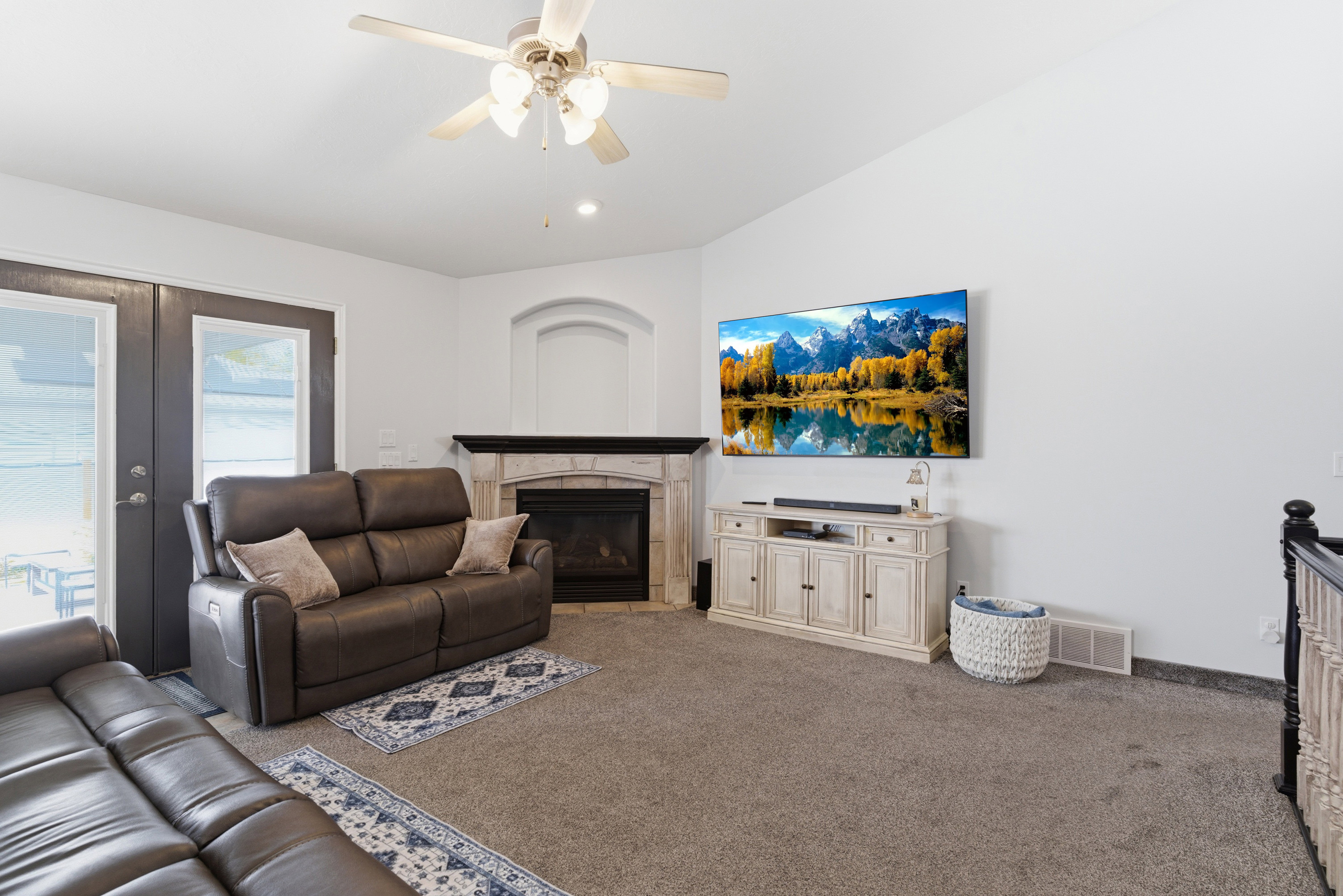 Carpeted living area with ceiling fan, a fireplace, vaulted ceiling, and french doors