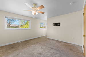 Carpeted spare room featuring baseboards and a ceiling fan