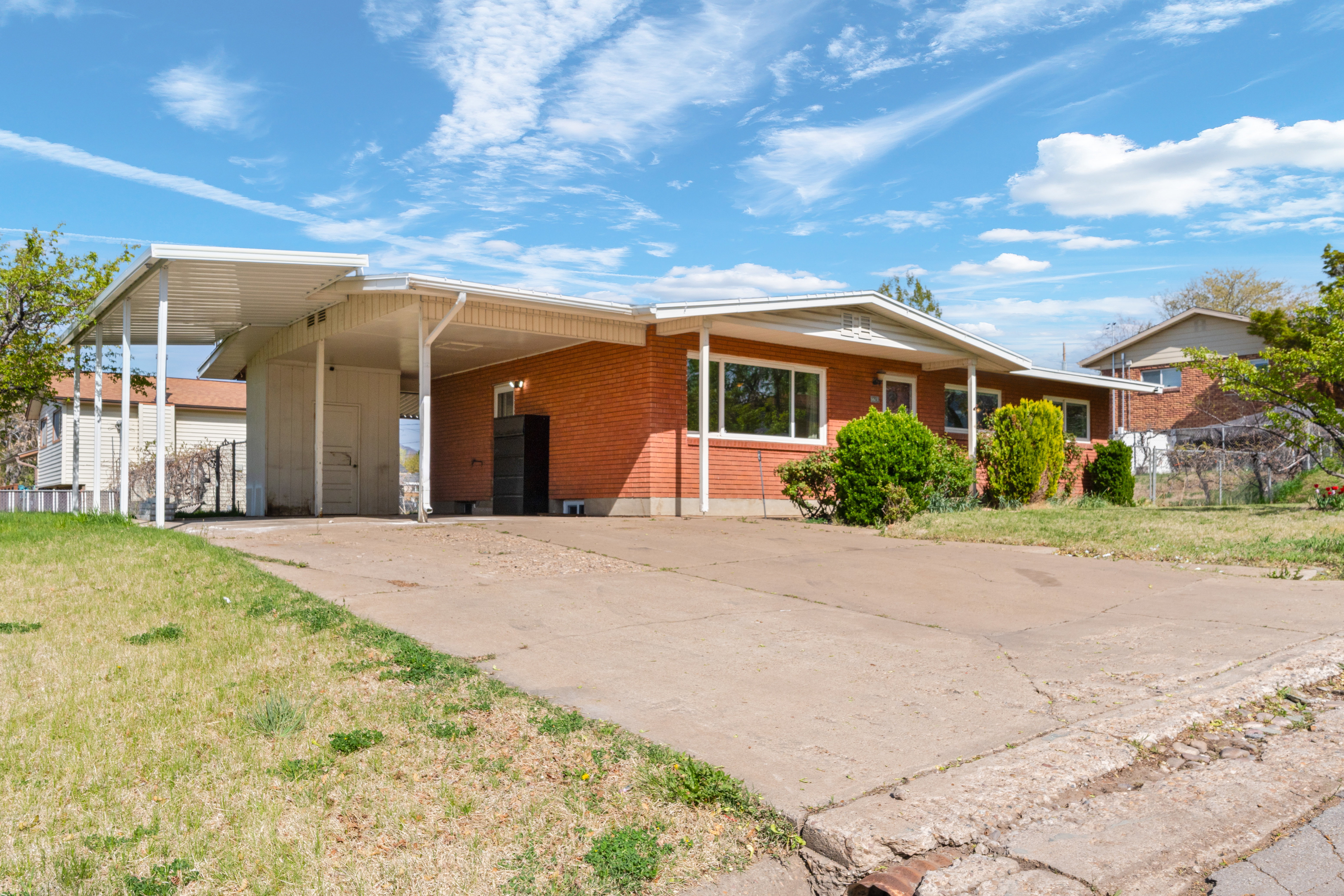 Ranch-style home with an attached carport, a front yard, driveway, and brick siding