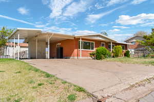 Ranch-style home with an attached carport, a front yard, driveway, and brick siding