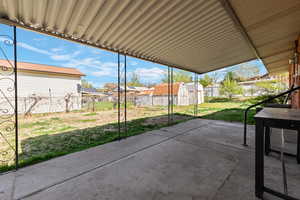 Fenced backyard featuring a patio, a storage unit, and a residential view