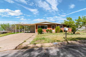 View of front of home featuring a front yard, a carport, driveway, and brick siding