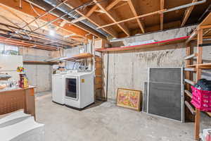Unfinished below grade area featuring washing machine and clothes dryer and freestanding refrigerator
