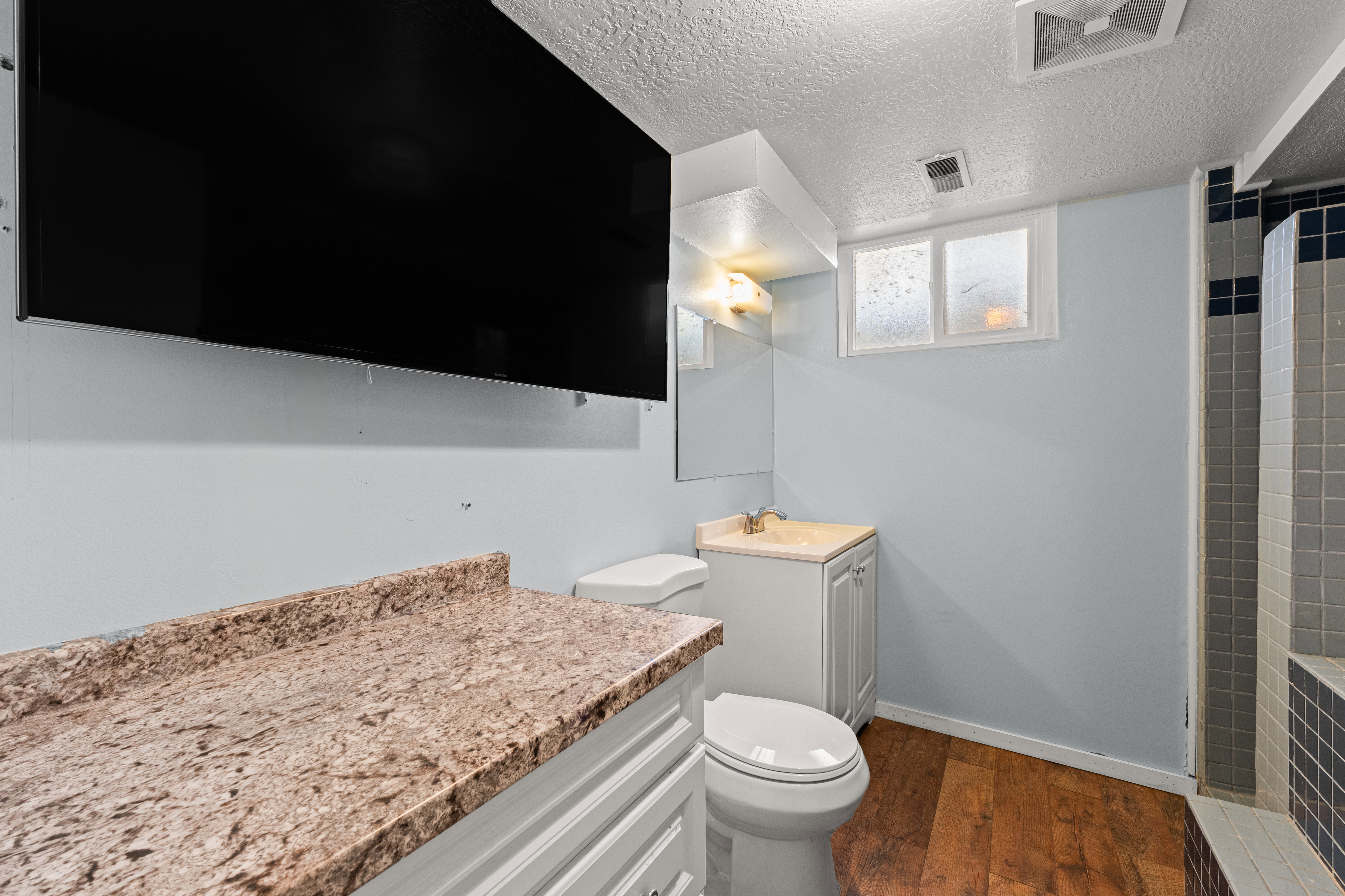 Bathroom with vanity, dark wood finished floors, a textured ceiling, and tiled shower
