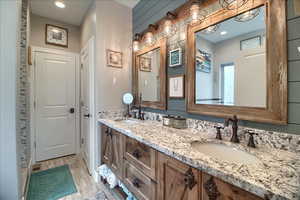 Bathroom with double vanity, light wood finished floors, and recessed lighting
