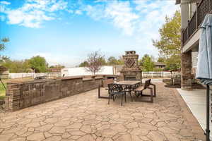 View of patio / terrace featuring an outdoor stone fireplace and outdoor dining area