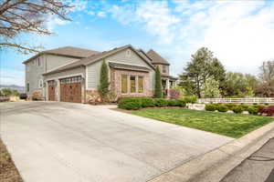 View of front of house with an attached garage, concrete driveway, and stone siding