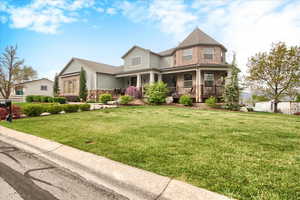 Victorian home with covered porch, a front lawn, brick siding, and a shingled roof