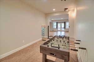 Game room featuring a raised ceiling, recessed lighting, french doors, and light colored carpet