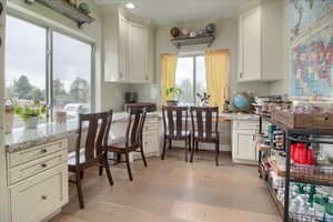 Kitchen with light stone countertops, light wood-style flooring, white cabinetry, and recessed lighting