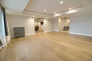 Unfurnished room with recessed lighting, light wood-style flooring, and a tray ceiling