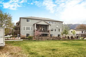 Back of property featuring a patio, a yard, stone siding, and a mountain view