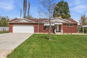 Single story home featuring driveway, an attached garage, brick siding, and a chimney