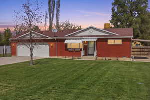 Ranch-style home featuring driveway, a chimney, brick siding, and an attached garage