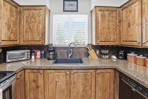 Kitchen featuring black dishwasher, wood finish cabinets, and light countertops
