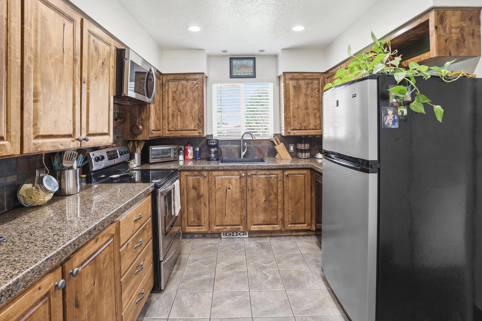 Kitchen with stainless steel appliances, wood finish cabinetry, a textured ceiling, and recessed lighting