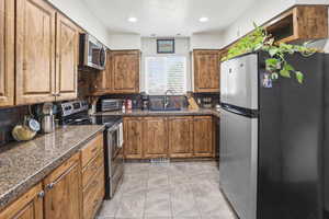 Kitchen with stainless steel appliances, wood finish cabinetry, a textured ceiling, and recessed lighting