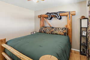 Bedroom featuring ceiling fan, wood finished floors, and a textured ceiling
