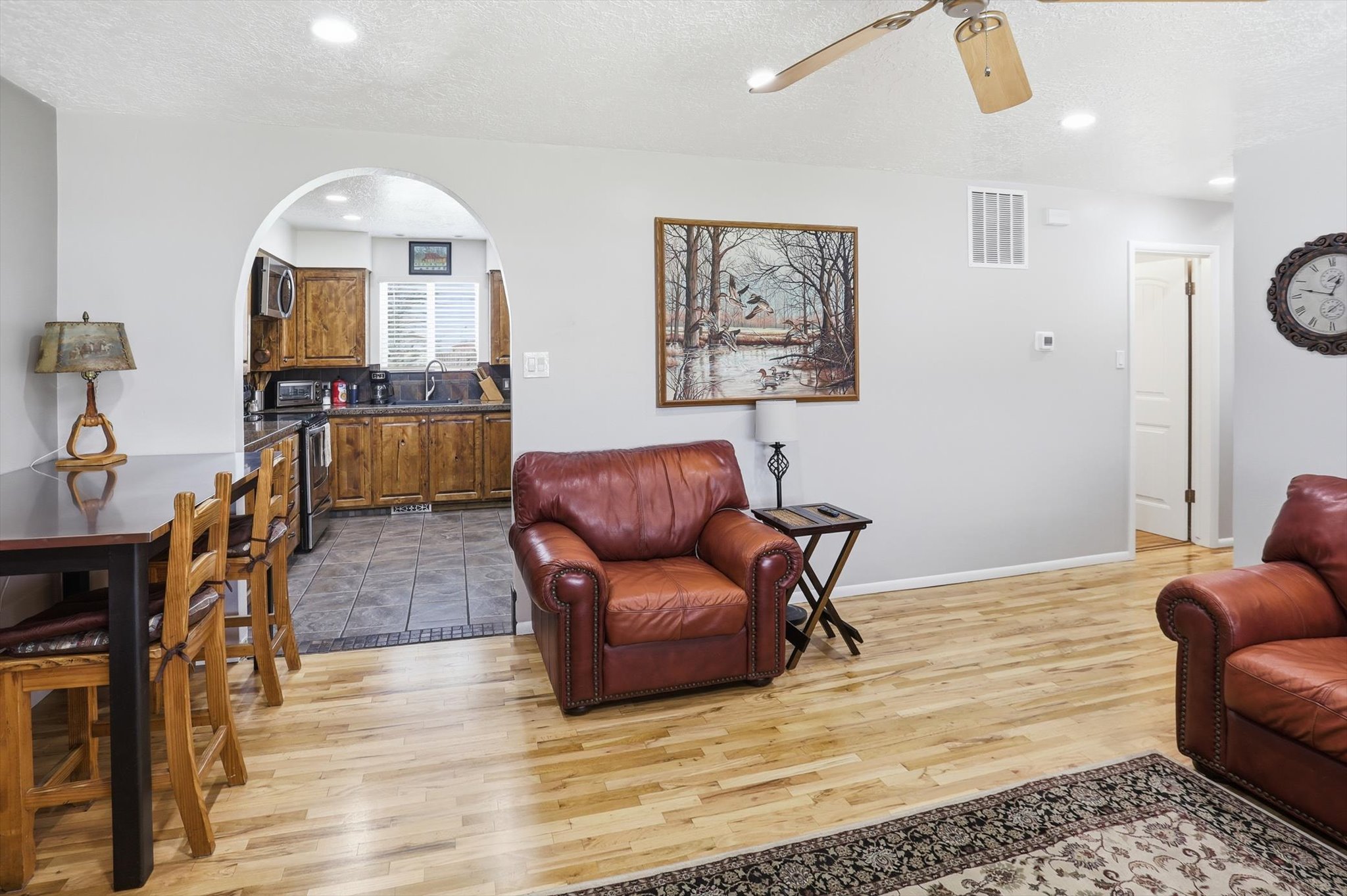 Living room with a textured ceiling, a ceiling fan, light wood-style flooring, arched walkways, and recessed lighting