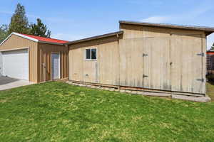 View of front of home with an outbuilding, a front yard, a metal roof, concrete driveway, and an attached garage