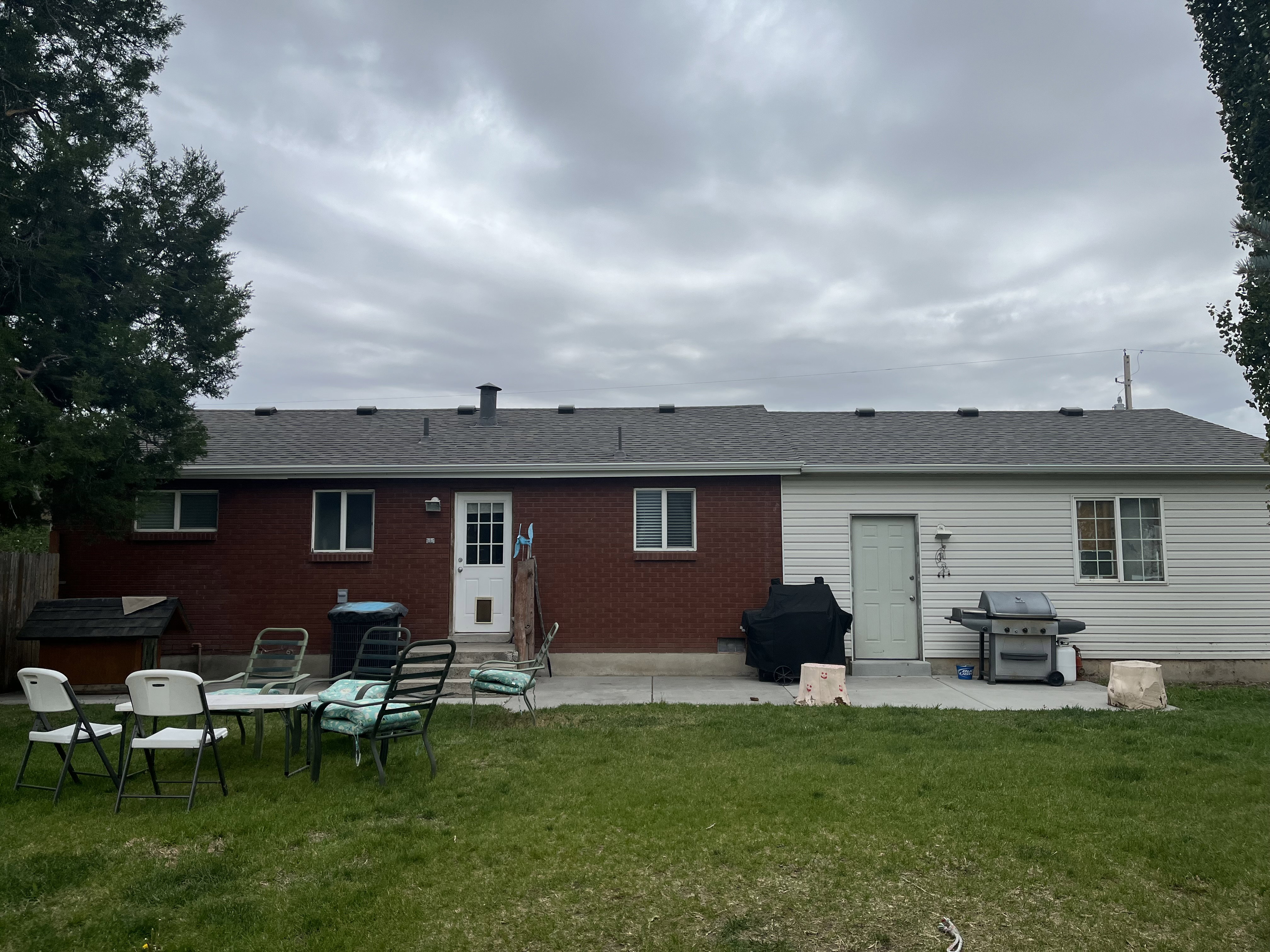 Expansive backyard featuring a manicured lawn, a concrete patio, and a combination of brick and siding exterior finishes