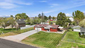 Single story home featuring driveway, a residential view, a fenced front yard, a garage, and brick siding