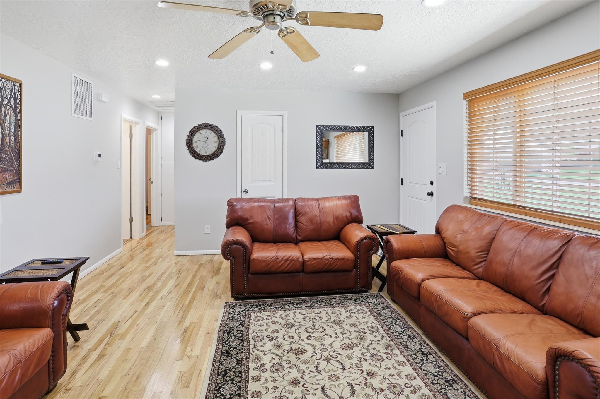 Living area with a ceiling fan, light wood-style flooring, recessed lighting, and a textured ceiling