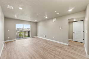 Unfurnished room featuring a textured ceiling, light wood-style flooring, recessed lighting, and a skyline view