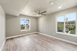 Bedroom featuring light wood finished floors, ceiling fan, a textured ceiling, and a smoke detector
