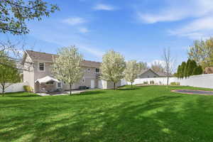 View of large back yard featuring an inground trampoline, garden area, terraced planters, and patio.