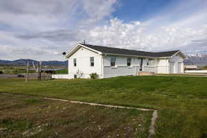 View of front of property with a mountain view, a front yard, and a garage