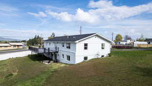 Rear view of property with a deck, a yard, board and batten siding, and a residential view