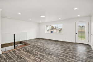 Unfurnished living room featuring dark wood finished floors, recessed lighting, and crown molding
