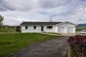 Ranch-style home with driveway, an attached garage, a front lawn, brick siding, and a mountain view