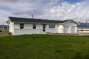 Ranch-style house featuring a mountain view, brick siding, an attached garage, and a front yard