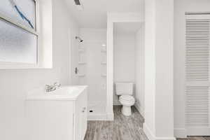 Full bathroom featuring vanity, a shower stall, light wood finished floors, and a closet