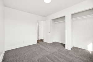 Unfurnished bedroom with dark colored carpet and two closets