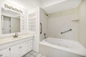 Bathroom featuring vanity, built in shelves, light tile patterned floors, and a combined bath / shower with jetted tub
