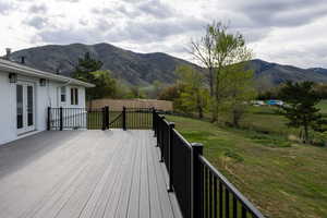 Wooden terrace with french doors, a mountain view, and a view of rural / pastoral area