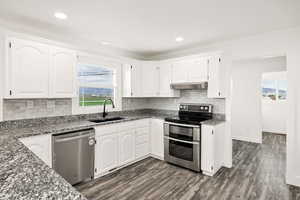 Kitchen with stainless steel appliances, dark stone counters, white cabinets, ornamental molding, and recessed lighting