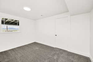 Empty room with baseboards and dark colored carpet