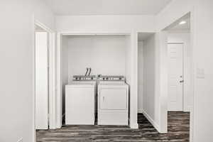 Laundry area featuring dark wood finished floors and independent washer and dryer