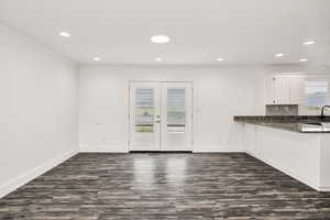 Kitchen featuring dark stone counters, dark wood finished floors, french doors, a peninsula, and healthy amount of natural light