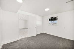 Empty room featuring dark colored carpet and baseboards