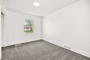 Unfurnished bedroom with baseboards and dark carpet