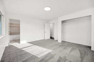 Unfurnished bedroom featuring carpet flooring, ensuite bath, and a closet