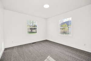 Spare room with dark colored carpet and healthy amount of natural light